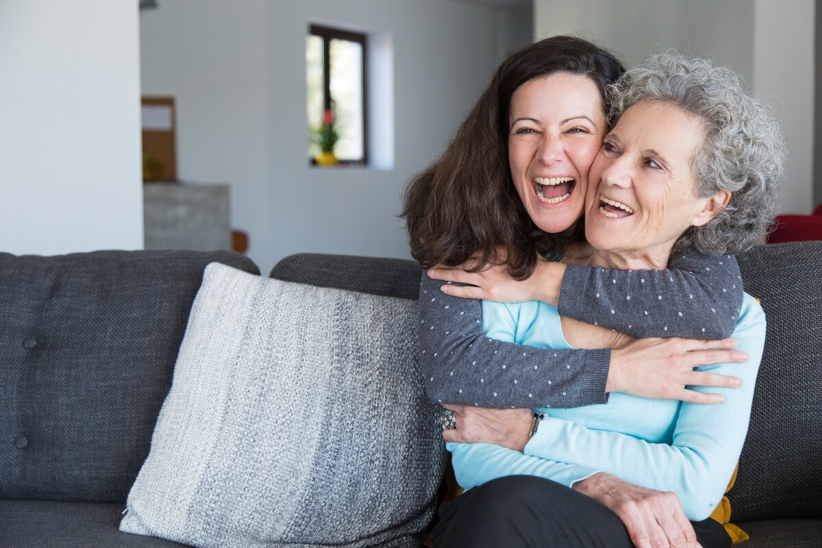 dos mujeres abrazadas sonriendo con protesis dental