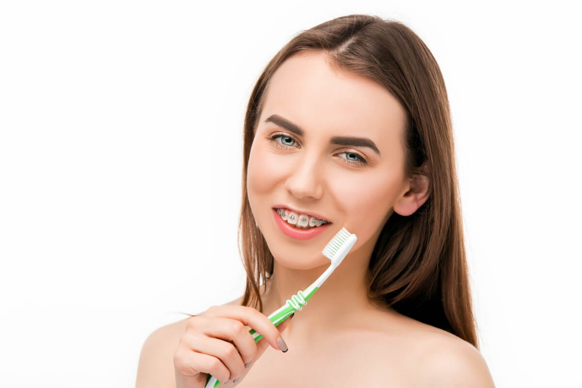 chica con brackets sujetando un cepillo de dientes