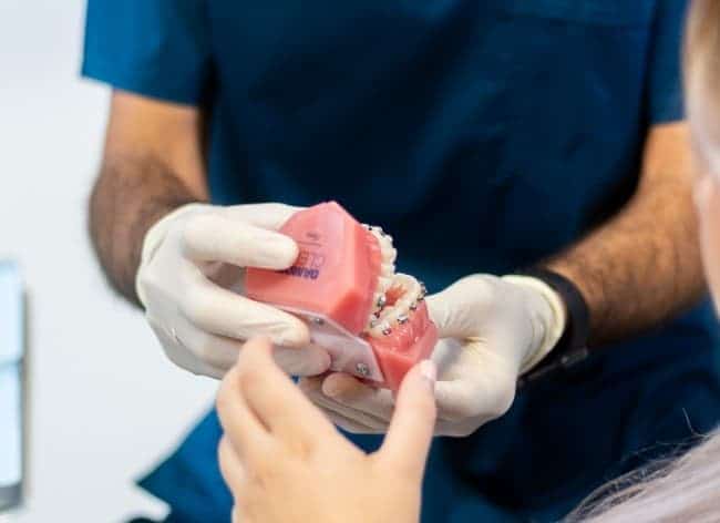 ortodoncista sujetando maqueta de dientes con brackets